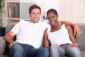 A man and woman sitting on the couch smiling.