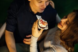 A man and woman eating cake at an event.